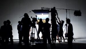 Filmteam i siluett arbetar med kamera och ljusutrustning i en studio